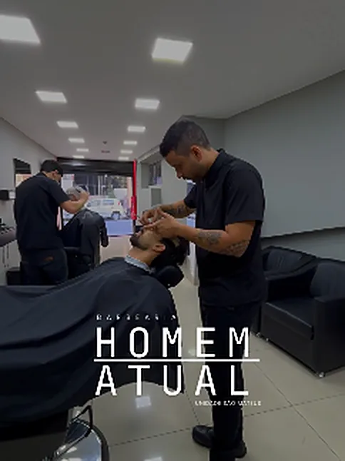 Barbeiro fazendo a barba de um cliente reclinado na cadeira