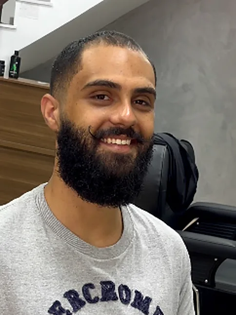 Cliente sorrindo com barba cheia e desenhada
