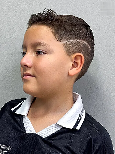 Menino com corte degradê e risco desenhado na lateral